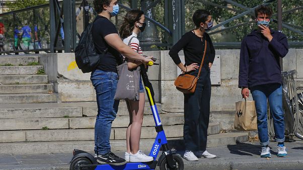 People wearing a protective face masks as precaution against the conoravirus ride a scooter in Paris People wearing a protective face masks as precaution against the conoravirus ride a scooter in Paris