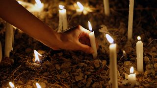 امرأة تضيء شمعة في ذكرى مرور شهر على انفجار بيروت الدموي