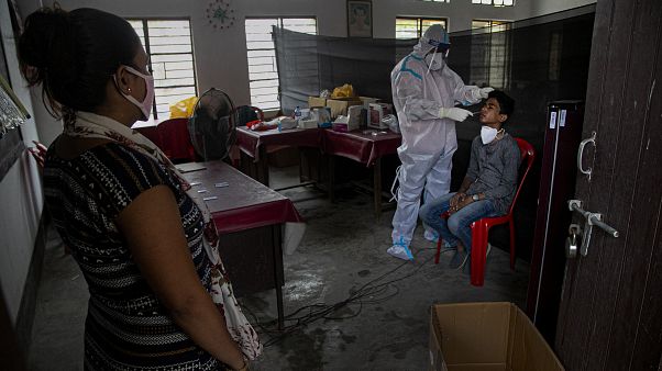 An Indian health worker takes a nasal swab sample of a man to test for COVID-19 as a woman waits for her turn in Gauhati, India, Sunday, Sept. 6, 2020.