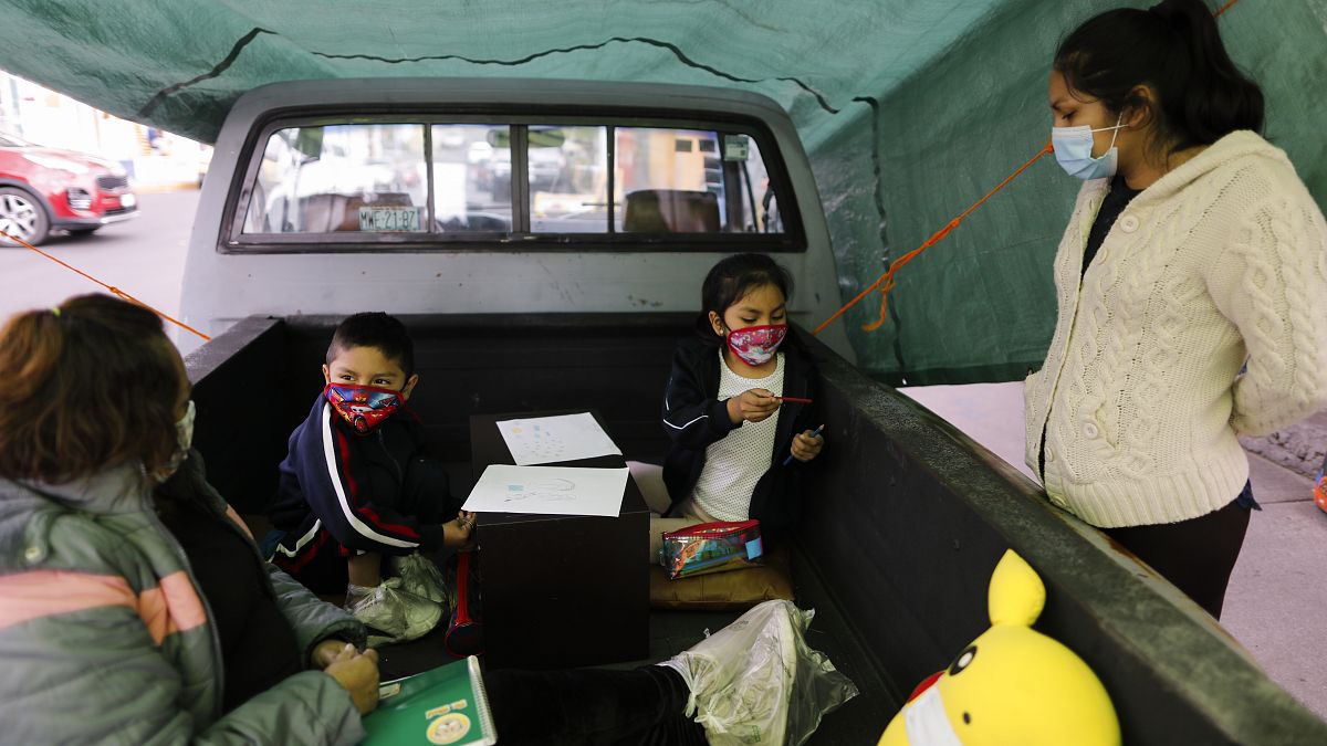 Dos niños trabajan con su profesora en el camión-escuela de Ciudad de México