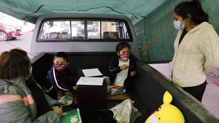 Dos niños trabajan con su profesora en el camión-escuela de Ciudad de México