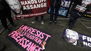 FILE - In this Thursday, Jan. 23, 2020 file photo, demonstrators supporting Julian Assange hold banners outside Westminster Magistrates Court in London. 