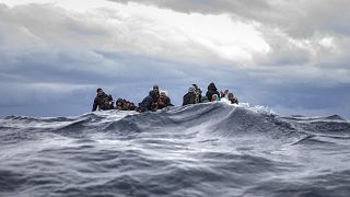 Migrants on an overcrowded wooden boat react as aid workers of the Spanish NGO Open Arms approach them in the Mediterranean Sea.