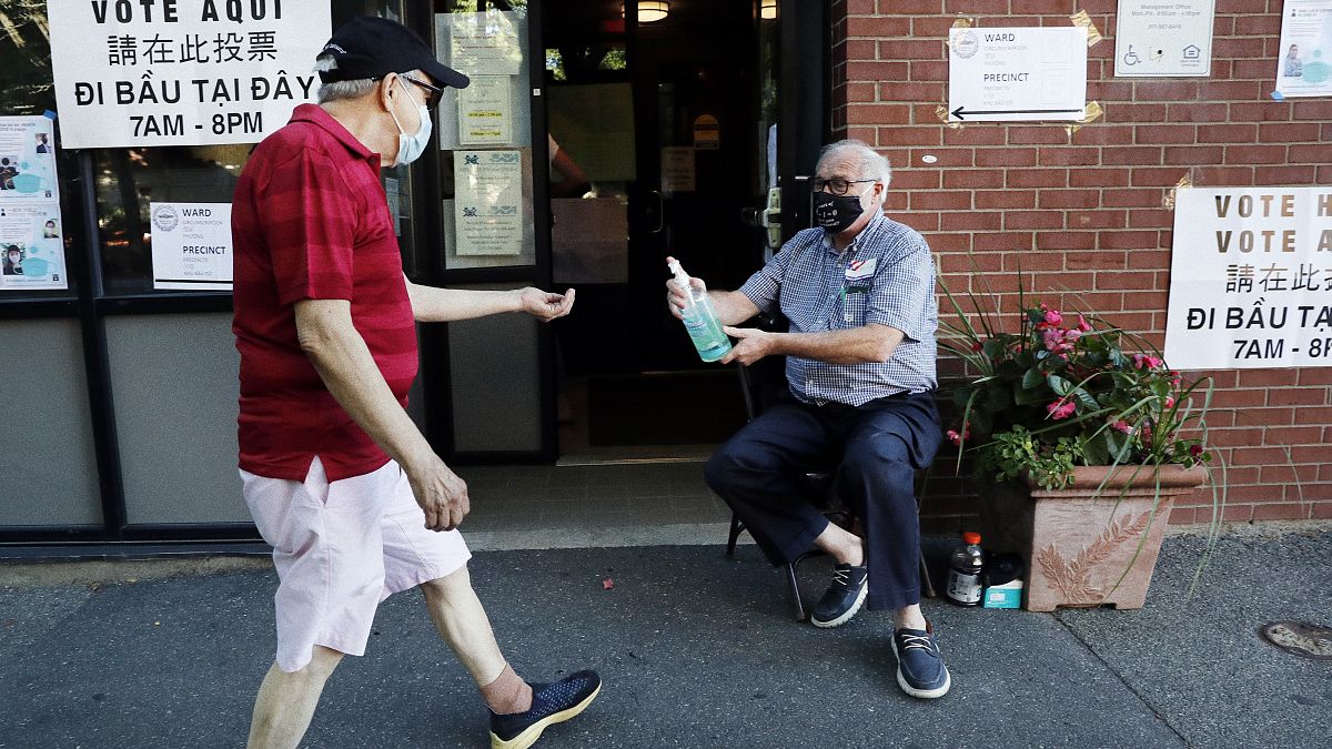أمريكي يتطوع لتقديم مطهر الأيدي إلى الوافدين إلى مركز للاقتراع خلال الانتخابات التمهيدية في بوسطن. 2020/09/01