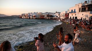 People gather as the sun sets in Little Venice on the Aegean Sea island of Mykonos, Greece, Sunday, Aug. 16, 2020.