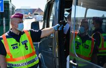 Egy belépő gépjármű utasainak testhőmérsékletét ellenőrzi egy rendőrök a hegyeshalmi határátkelőnél 2020. szeptember 5-én. 