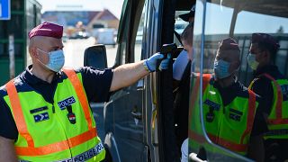 Egy belépő gépjármű utasainak testhőmérsékletét ellenőrzi egy rendőrök a hegyeshalmi határátkelőnél 2020. szeptember 5-én.