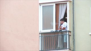 Un joven fuma un cigarro en el balcón de su casa en uno de los barrios que ha entrado en cuarentena