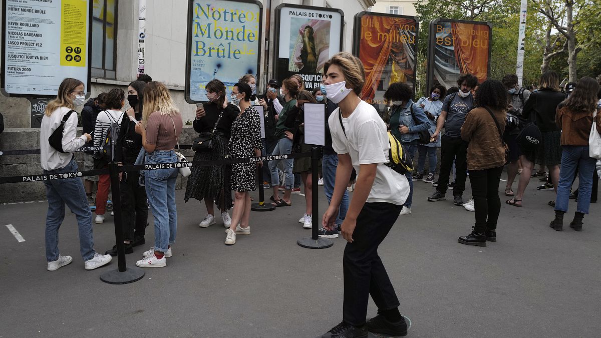 Un joven pasa en monopatín ante la gente que hace cola ante el Palacio de Tokio en París