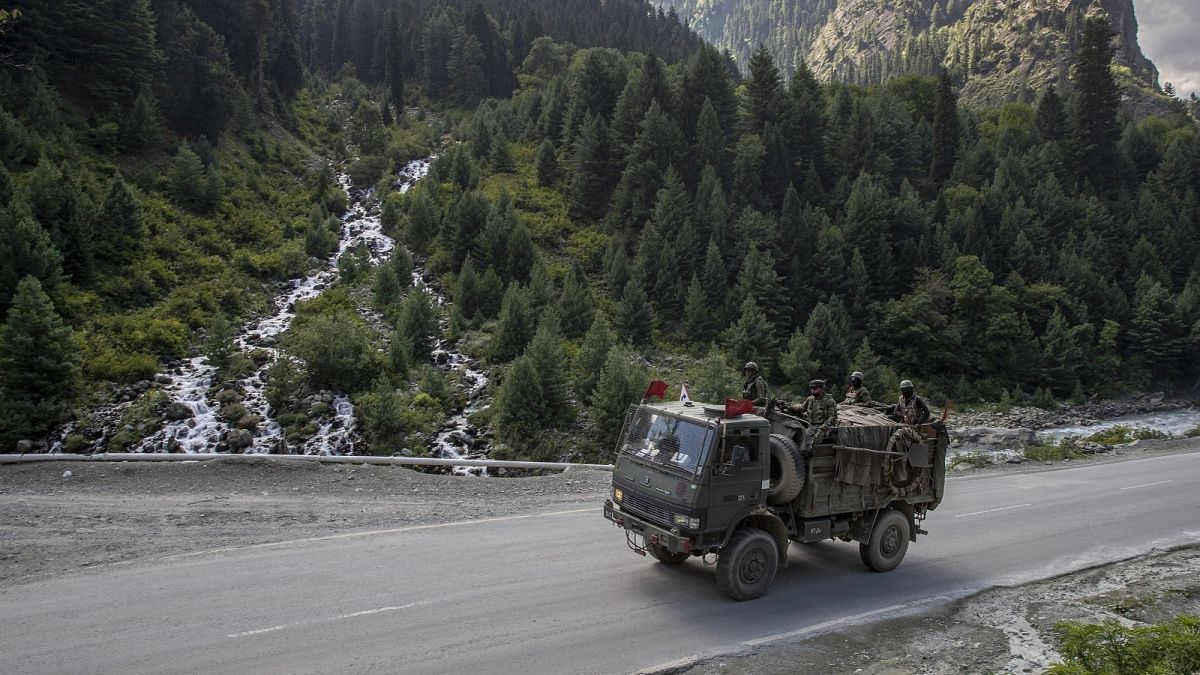 Indian army soldiers keep guard on top of their vehicle as their convoy moves on the Srinagar- Ladakh highway at Gagangeer, northeast of Srinagar, Indian-controlled Kashmir.