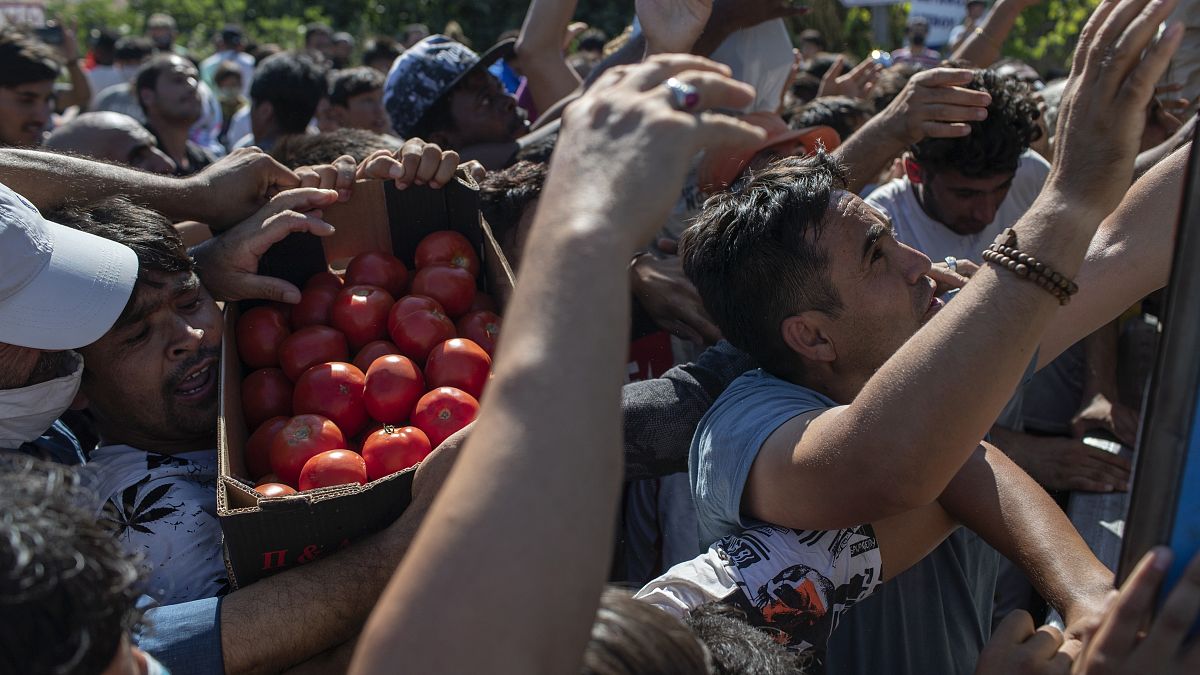Migrants argue for a crate of tomatoes during a food distribution on the northeastern island of Lesbos, Greece, Thursday, Sept. 10, 2020.