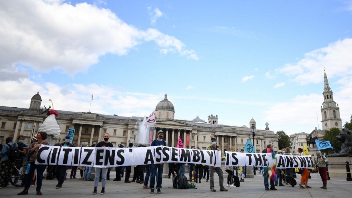 Activists from the climate protest group Extinction Rebellion hold up a banner displaying "Citizens' Assembly is the Answer' in Trafalgar Square in central London.