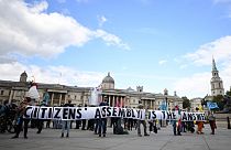 Activists from the climate protest group Extinction Rebellion hold up a banner displaying "Citizens' Assembly is the Answer' in Trafalgar Square in central London.