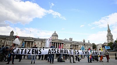 Activists from the climate protest group Extinction Rebellion hold up a banner displaying "Citizens' Assembly is the Answer' in Trafalgar Square in central London. Activists from the climate protest group Extinction Rebellion hold up a banner displaying "Citizens' Assembly is the Answer' in Trafalgar Square in central London.