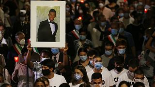 A man holds up a picture of Willy Monteiro Duarte during a torch light procession in Paliano, Italy, on September 9, 2020