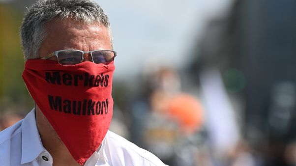 A participant at a demonstration against COVID-19 restrictions wears a scarf reading 'Merkel's muzzle', Munich, Germany. September 12, 2020. A participant at a demonstration against COVID-19 restrictions wears a scarf reading 'Merkel's muzzle', Munich, Germany. September 12, 2020.
