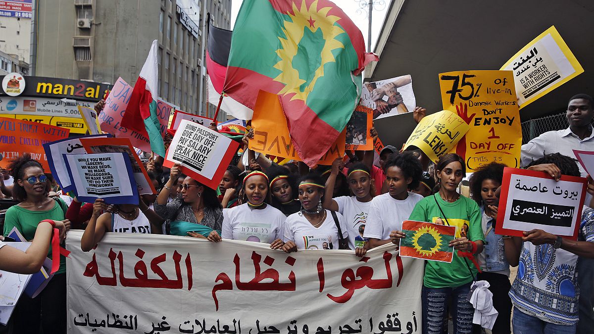 عاملات منازل مهاجرات يحملن لافتة باللغة العربية كتب عليها "ألغوا نظام الكفالة"، خلال تجمع  للاحتفال باليوم العالمي للعمال