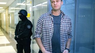 In this Dec. 26, 2019, file photo, Russian opposition leader Alexei Navalny speaks to the media in front of a security officer