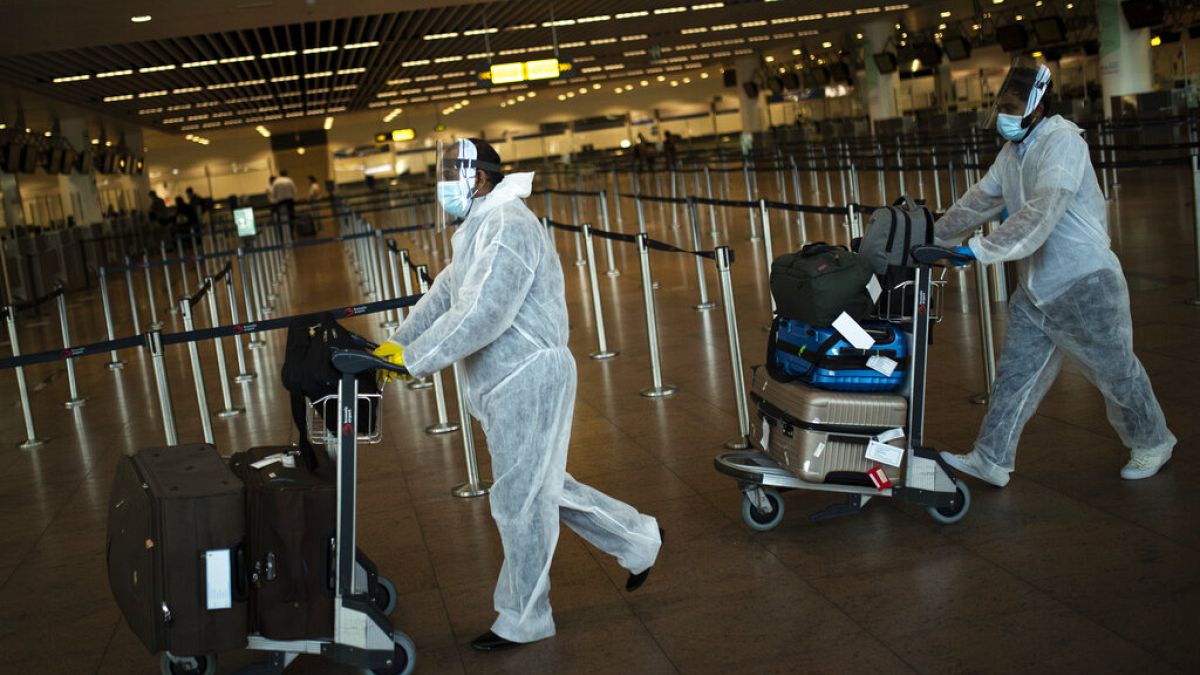 Pasajeros con equipamiento de protección personal completo en el aeropuerto Zaventem de Bruselas