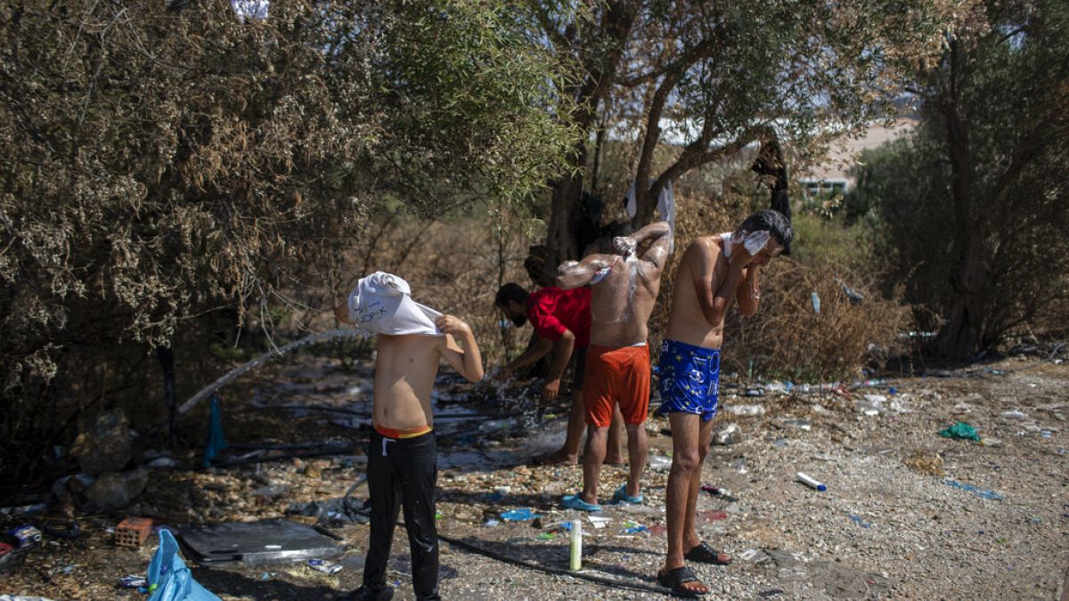 Migrants and refugees wash in a field near the burned Moria camp on island of Lesbos, Greece