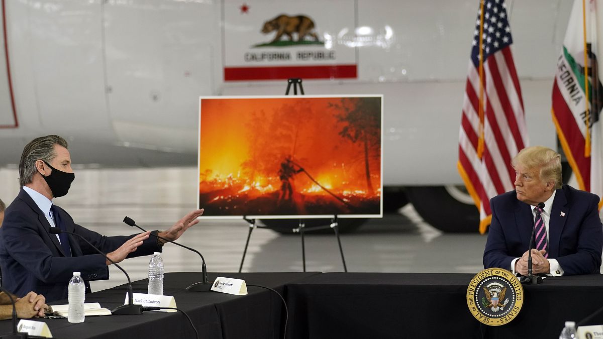 President Donald Trump listens as California Gov. Gavin Newsom speaks during a briefing at Sacramento McClellan Airport, California, Sept. 14, 2020, on western wildfires.