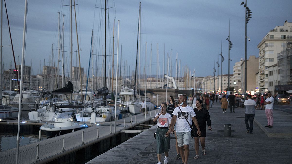 People stroll along Marseille's Old Port, southern France, July 25, 2020. Marseille and Bordeaux are tightening restrictions amid a sharp uptick in coronavirus cases.