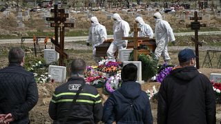 عمال يرتدون بدلات واقية ويحملون ضحية من ضحايا كوفيد-19 في مقبرة مخصصة لوفيات  الفيروس التاجي خارج سانت بطرسبرغ، روسيا.