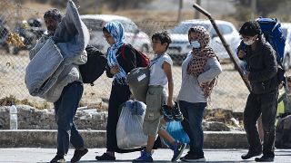 A family carrying their belongings walk toward a new temporary camp, set up to shelter refugees from the burnt Moria refugee camp, on the island of Lesbos