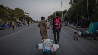 Des migrants tirent leurs affaires alors que les rescapés de l'incendie du camp de Moria à Lesbos campent comme ils peuvent le long de la route, le 15 septembre 2020