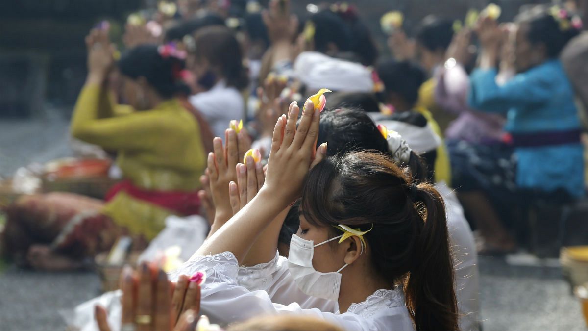 Women wearing face masks as a precaution against the new coronavirus outbreak pray during a Hindu ritual prayer at a temple in Bali, Indonesia