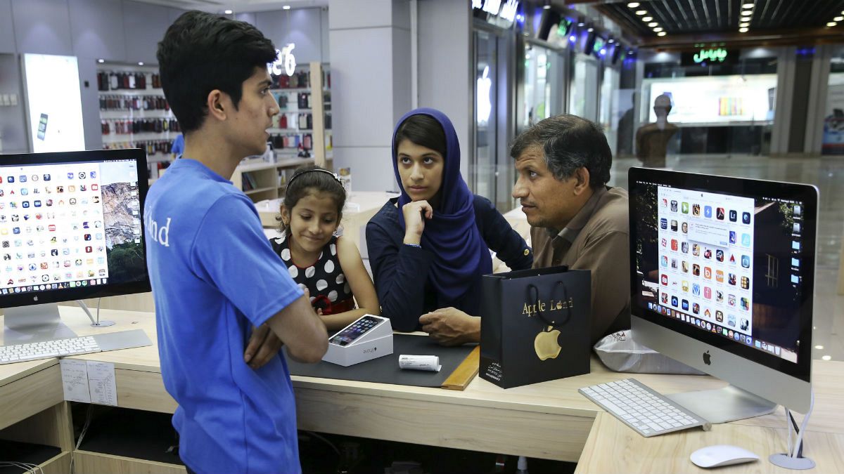  An Iranian shopkeeper talks to his costumers thinking of buying an iPhone in an electronics shop in Tehran, Iran