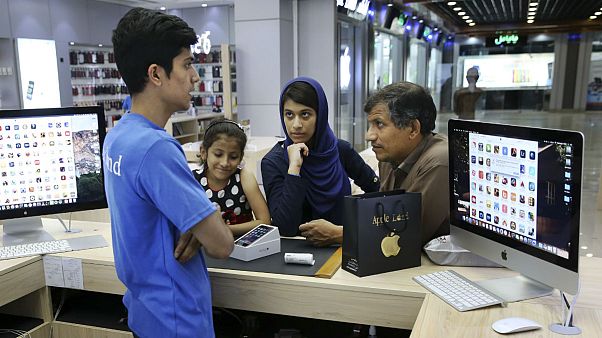 An Iranian shopkeeper talks to his costumers thinking of buying an iPhone in an electronics shop in Tehran, Iran An Iranian shopkeeper talks to his costumers thinking of buying an iPhone in an electronics shop in Tehran, Iran