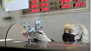 An official wearing a face mask for protection against the coronavirus, selling US dollar at a currency exchange office