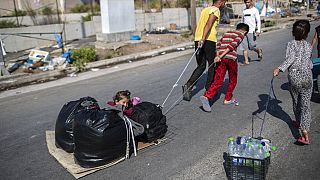 A child sits between plastic bags as migrants pull their belongings in Kara Tepe, near Mytilene the capital of the northeastern island of Lesbos, Greece, Sept 2020