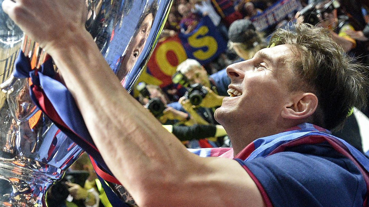 In this June 6, 2015 file photo, Barcelona's Lionel Messi smiles to his mirror in the trophy after winning the Champions League final football match against Juventus.