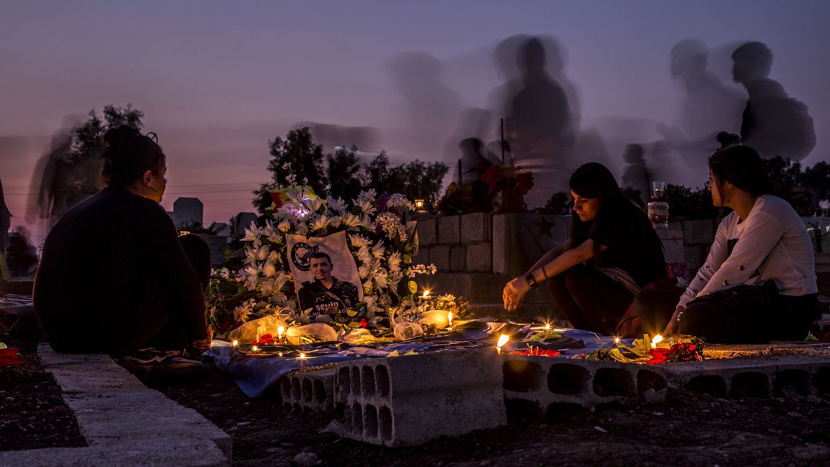 أقارب يزورون قبر في بلدة القامشلي شمال سوريا. 