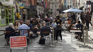 People sit outside on a street closed to traffic to try to reduce the spread of coronavirus in London, Saturday, Sept. 19, 2020.