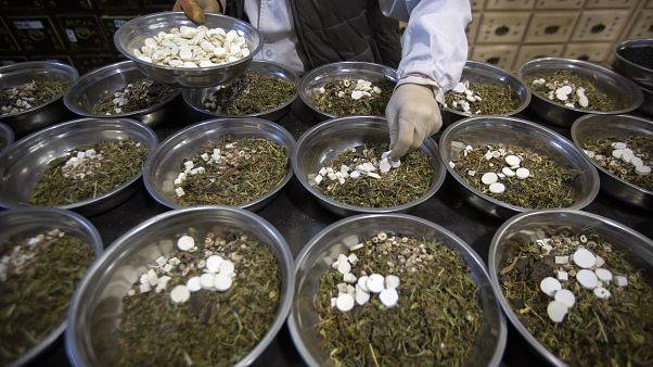 عامل بصدد تجميع مكونات مستحضرات الطب الصيني التقليدي في أوعية في عيادة بواي تنغ للطب الصيني التقليدي في بيكين. 2020/03/13 عامل بصدد تجميع مكونات مستحضرات الطب الصيني التقليدي في أوعية في عيادة بواي تنغ للطب الصيني التقليدي في بيكين. 2020/03/13