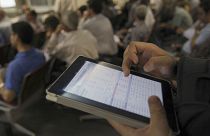 An Iranian shareholder monitors shares prices on his tablet at the Tehran Stock Exchange in Tehran, Iran