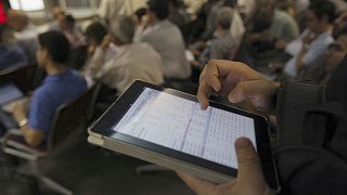 An Iranian shareholder monitors shares prices on his tablet at the Tehran Stock Exchange in Tehran, Iran