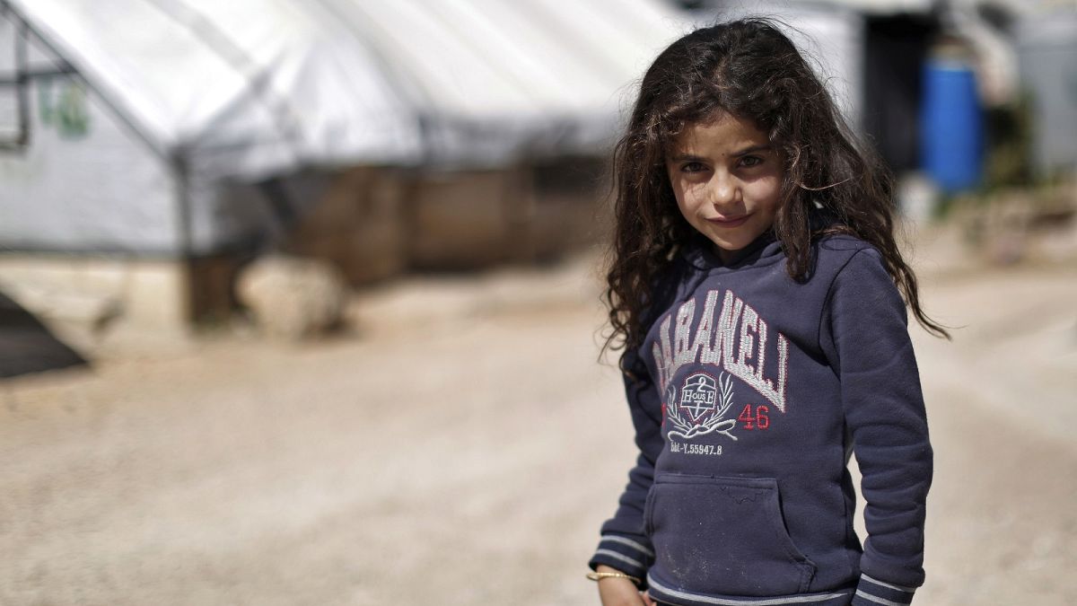 A Syrian girl poses for a picture at a refugee camp in the eastern Lebanese border town of Arsal, Lebanon.