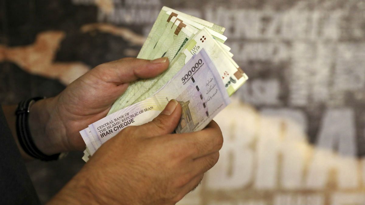 A man counts his banknotes and traveler checks in Tehran, Iran