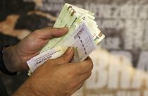 A man counts his banknotes and traveler checks in Tehran, Iran