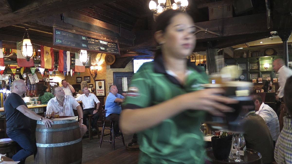 نادلة تقدم بيرة للعملاء في مطعم في دبي، الإمارات العربية المتحدة