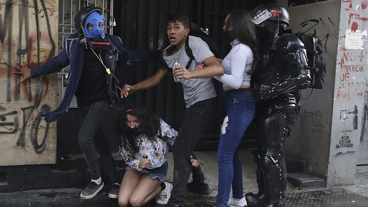 Un policía junto a tres manifestantes durante los disturbios en Bogotá, Colombia