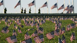 Activists from the COVID Memorial Project mark the deaths of 200,000 lives lost in the US to COVID-19 after placing thousands of small American flags in Washington DC.