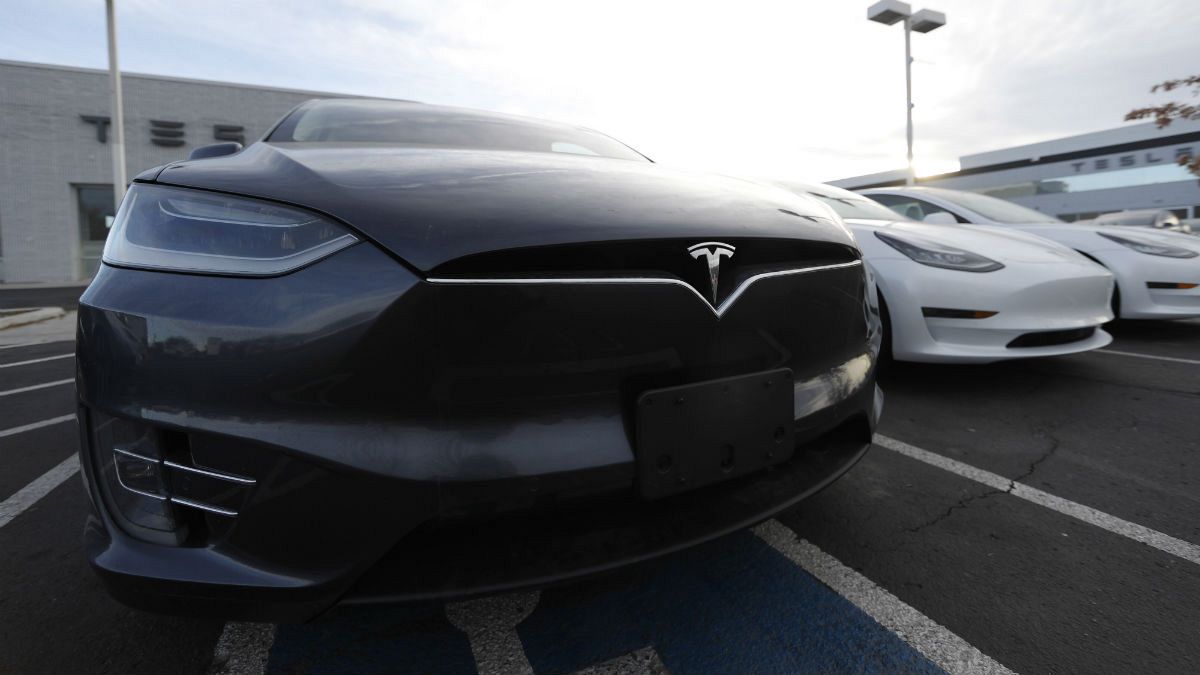 A Model X sports-utility vehicle sits with other vehicles at a Tesla dealership in Littleton