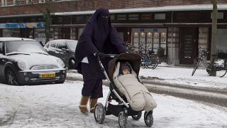 FILE - In this Monday Jan. 21, 2013 file photo, a woman wearing a full-face veil known as niqab, pushes a baby stroller on snow-covered streets in Amsterdam, Netherlands.