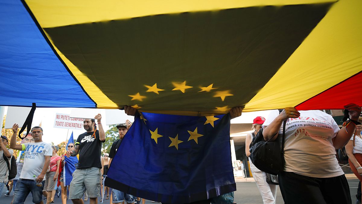 People carry Romanian and European Union flags as they gather for an anti-government protest outside the government headquarters in Bucharest, Romania, August 10, 2019.