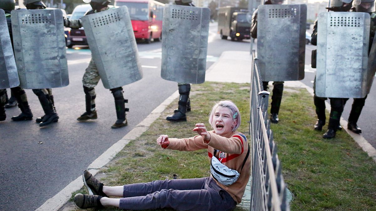 A woman reacts as she sits in front of law enforcement officers during a rally to protest against the presidential inauguration in Minsk on September 23, 2020. 